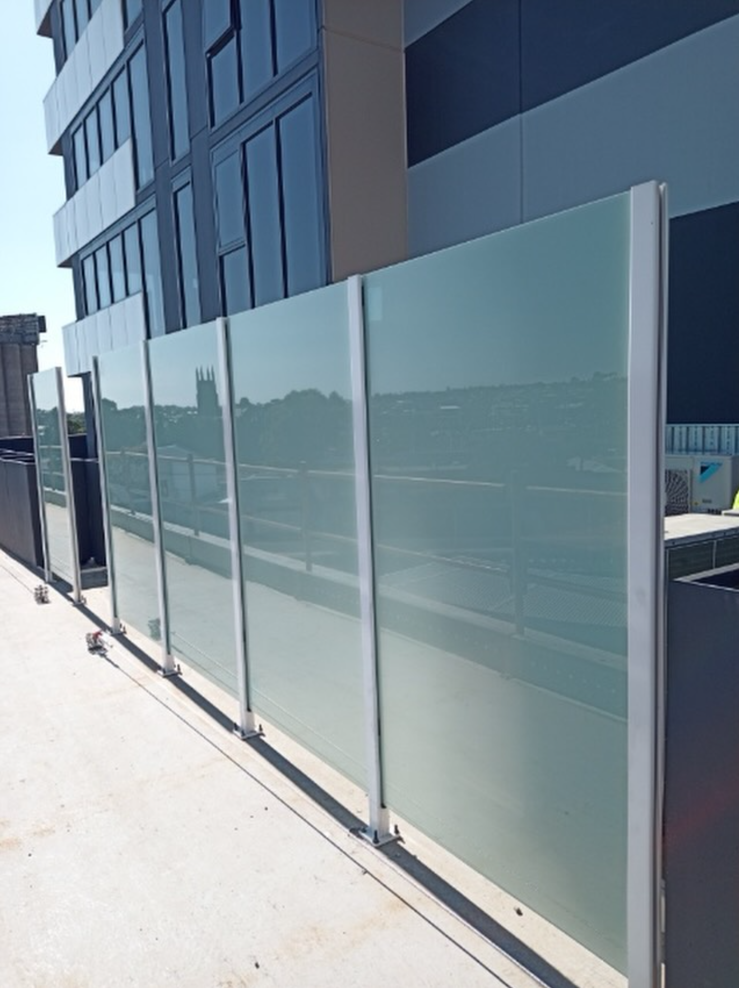 Framed frosted glass privacy screens on commercial rooftop